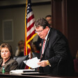 Randy Fine stands with a paper in hand as people look on