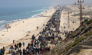 Thousands of people walk along a beach